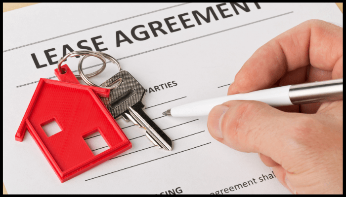 Hand signing lease agreement with house keys, representing rental obligations before end of lease cleaning.