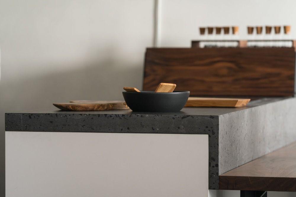 A bowl of food is sitting on a terrazzo counter next to a wooden cutting board.
