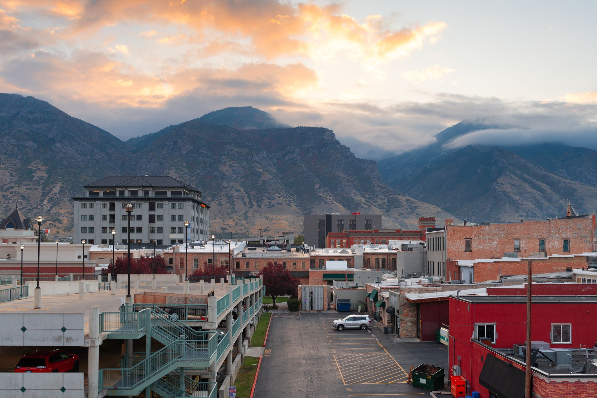 City buildings with mountains in the background at dusk.