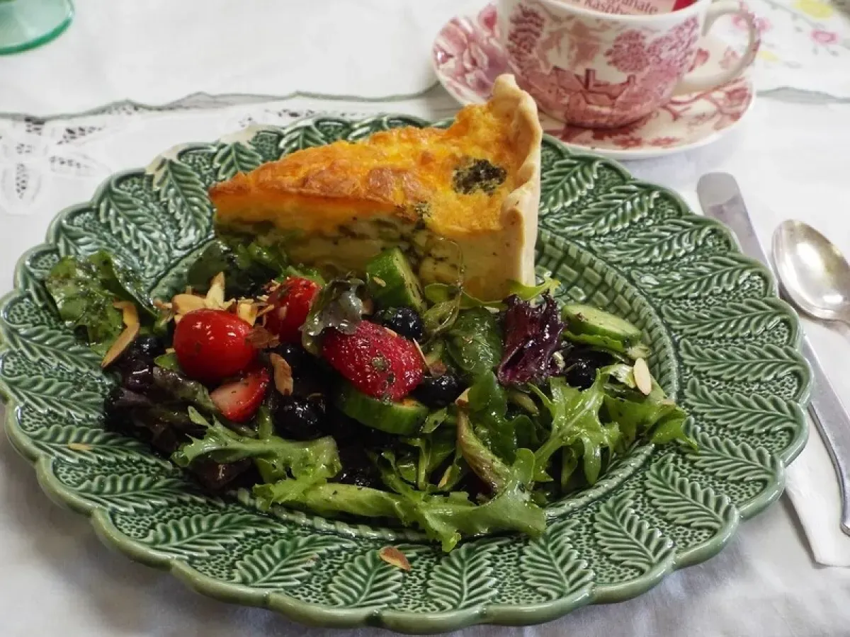 A green plate with a salad and a quiche on it.