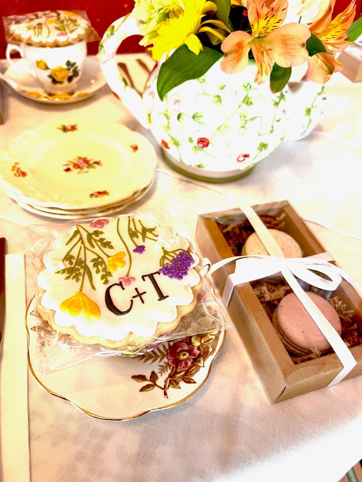 A table topped with plates , cups , and a cookie with the letters c + t on it.