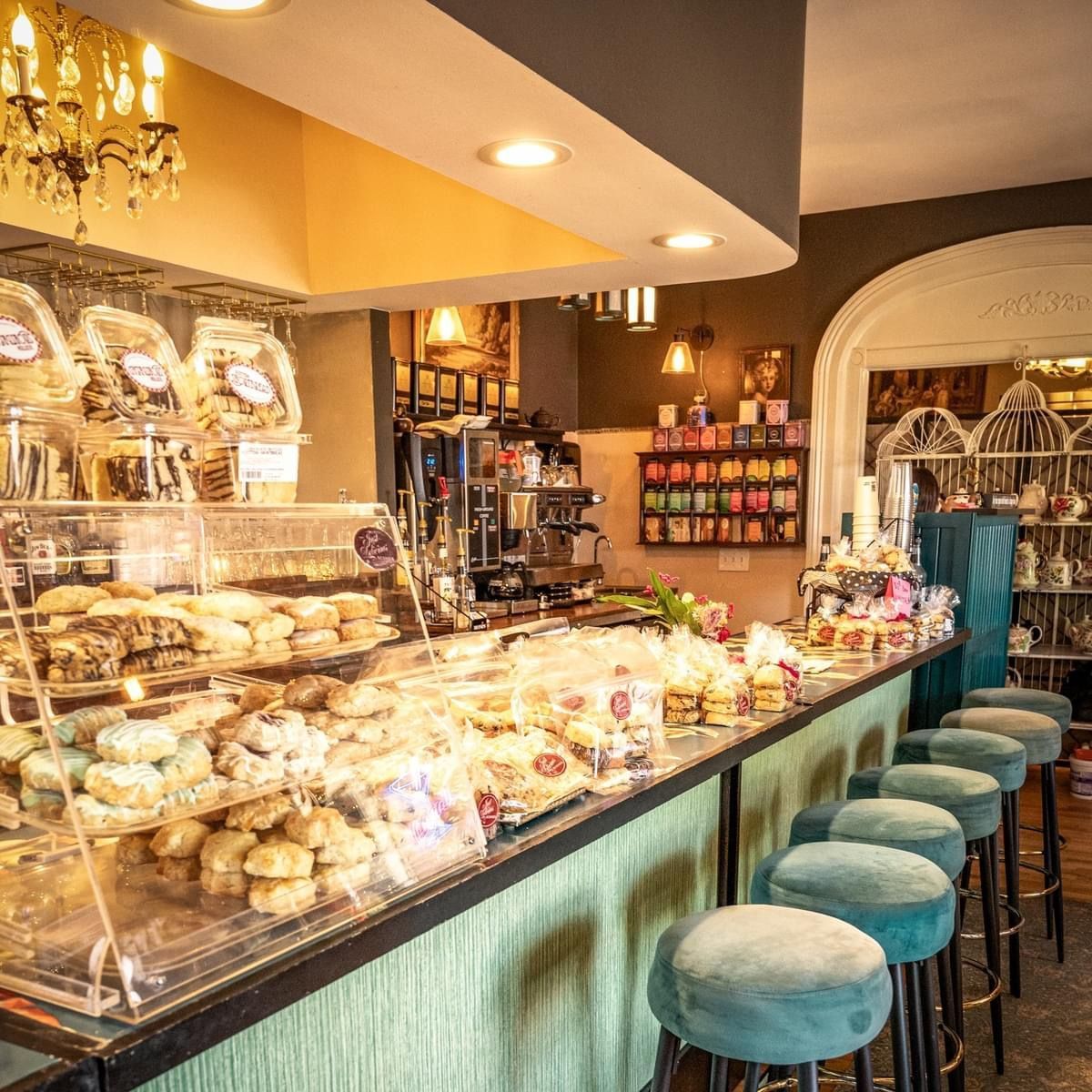 A bakery with a long counter filled with lots of food and stools.