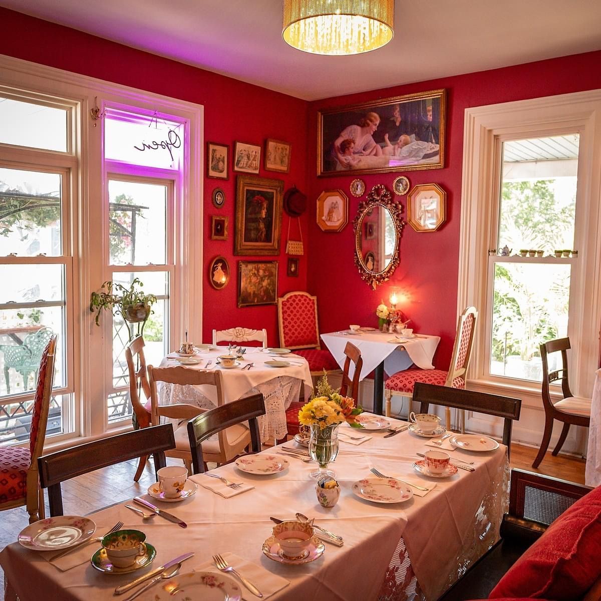 A dining room with red walls and tables and chairs.