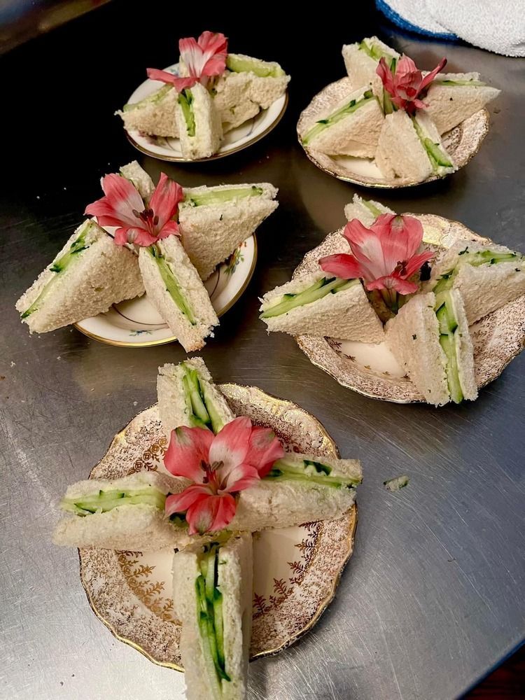 Four plates of sandwiches with flowers on them on a table