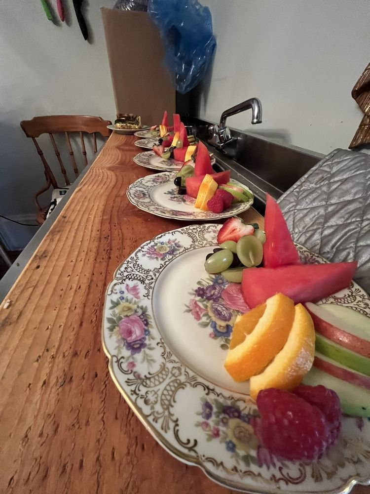 Plates of fruit are lined up on a wooden counter