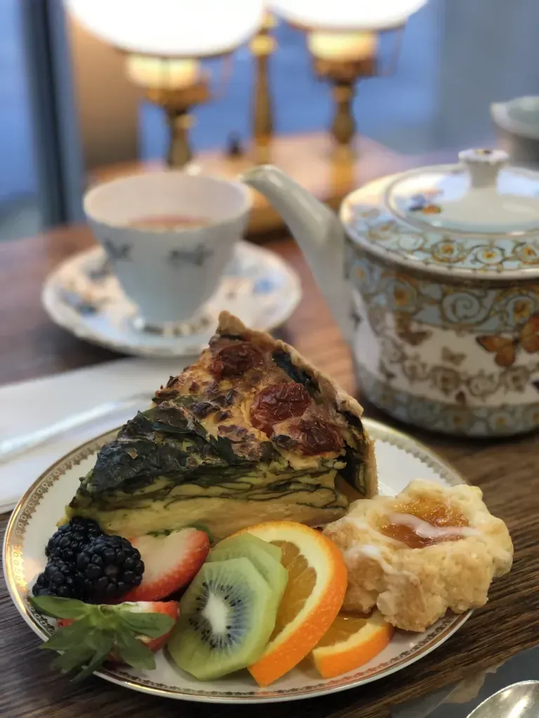 A plate of food with a slice of quiche and fruit on it.