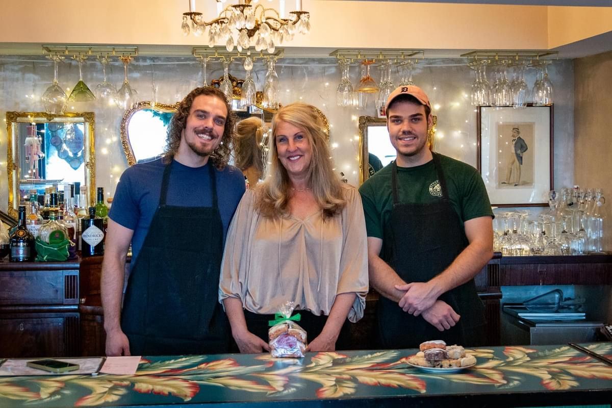 Three people are standing in front of a bar.