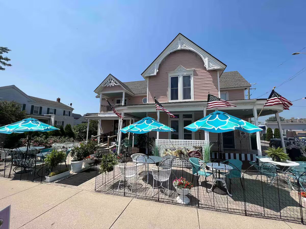 A pink house with blue umbrellas and tables in front of it.