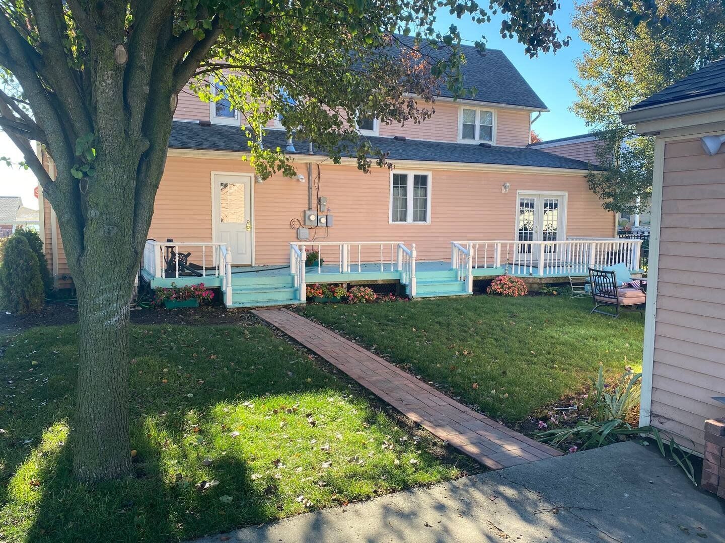 A pink house with a blue porch and a tree in front of it.