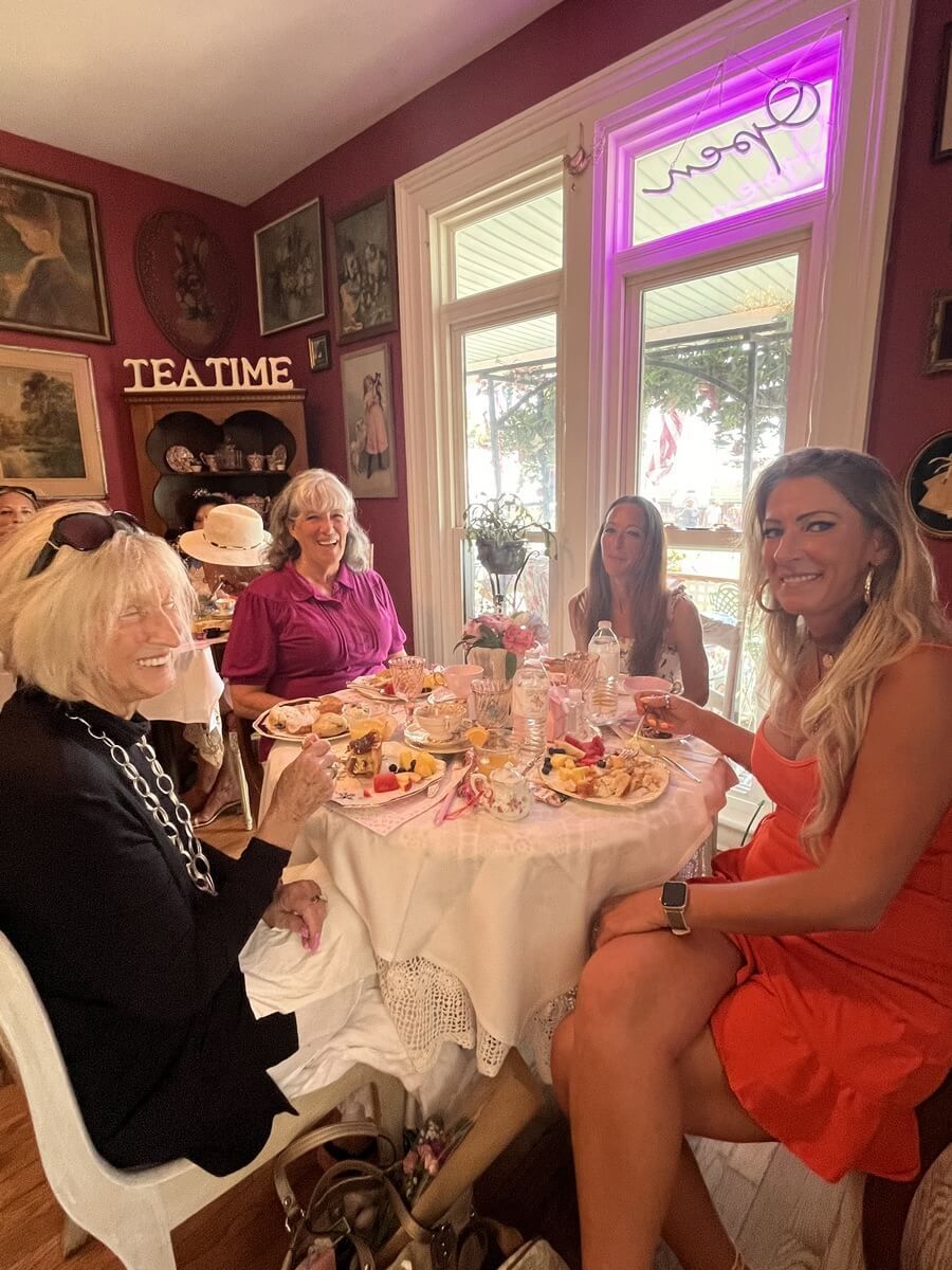 A group of women are sitting at a table drinking tea.