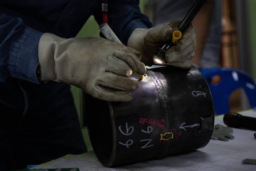 A Man is Welding a Piece of Metal on a Table — Febos Welding and Engineering In Corrimal, NSW