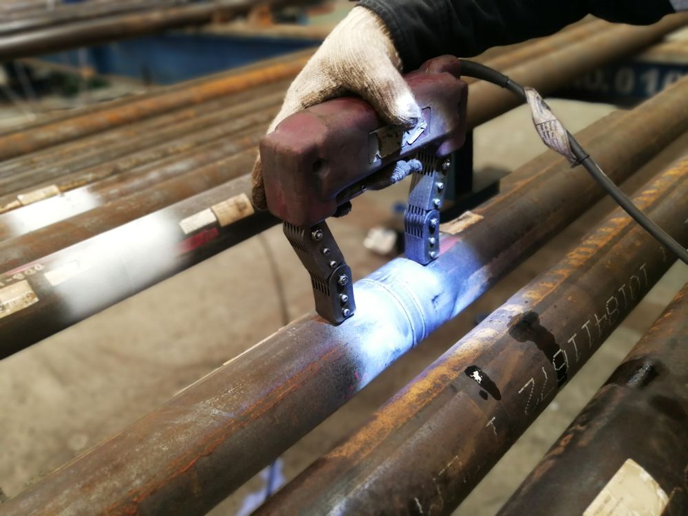 A Person is Holding a Magnet Over a Metal Pipe — Febos Welding and Engineering In Corrimal, NSW
