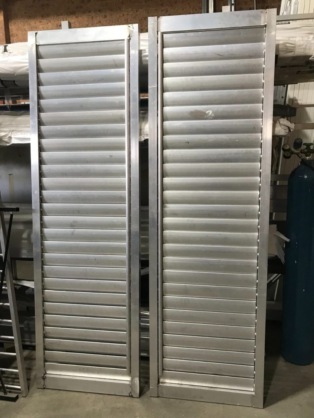 A Pair of Aluminum Shutters Are Sitting Next to Each Other in a Room — Febos Welding and Engineering In Corrimal, NSW