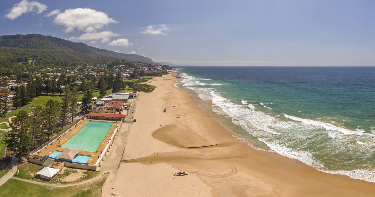 An Aerial View of a Beach With a Pool and Mountains in the Background — Febos Welding and Engineering In Thirroul, NSW