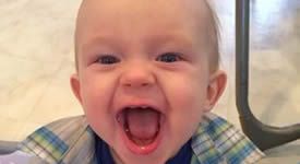 A baby is sitting in a high chair with his mouth open.