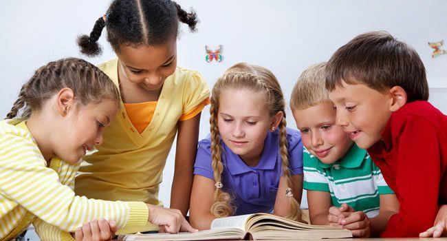 A group of children are reading a book together.