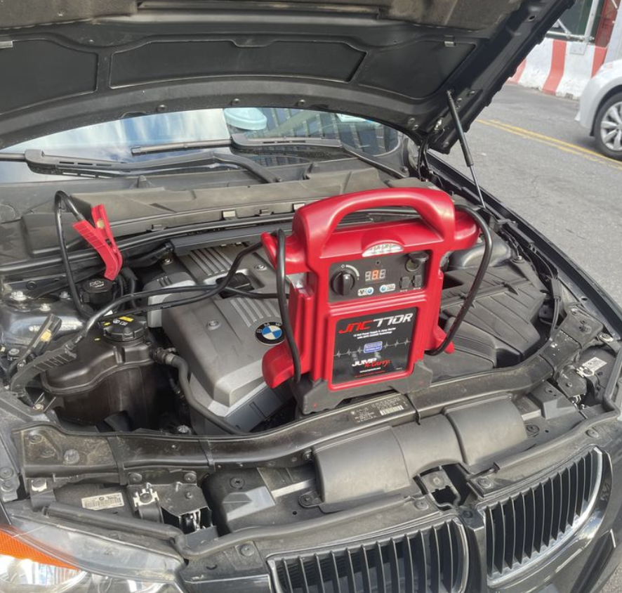 Green tow truck carrying a black car on a city street.