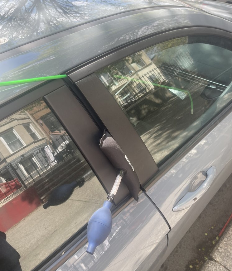 Green tow truck carrying a black car on a city street.