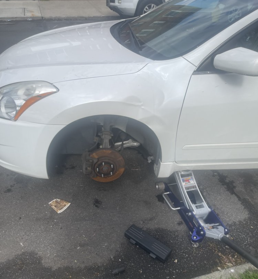 Green tow truck carrying a black car on a city street.
