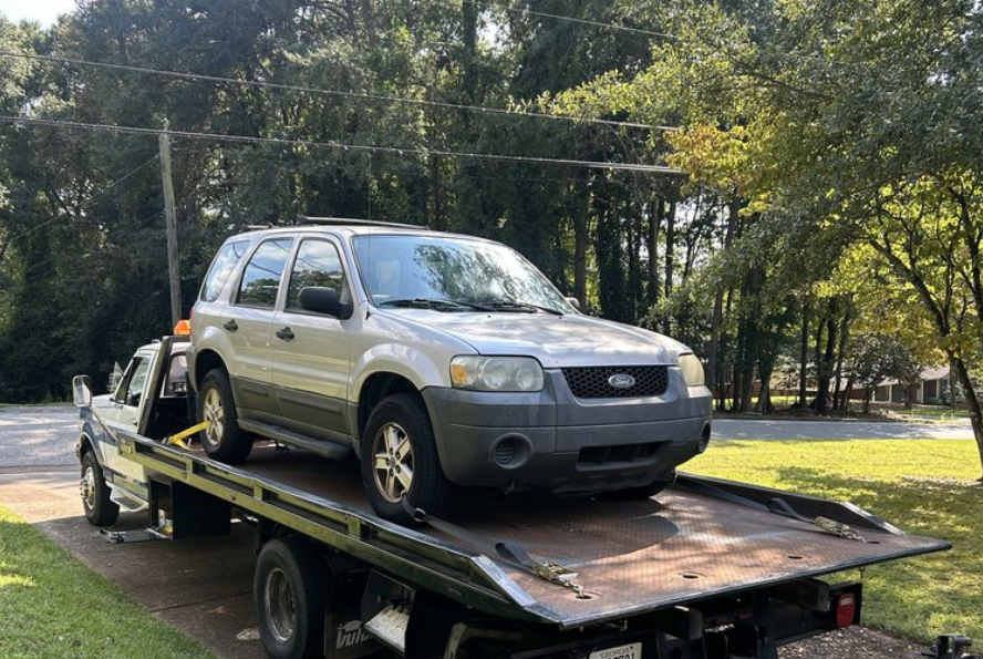 A beige SUV on the back of a white tow truck.