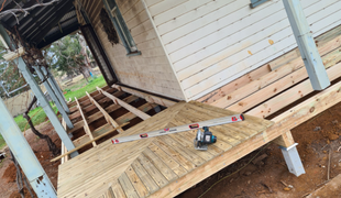 Wooden porch under construction; level on completed section.