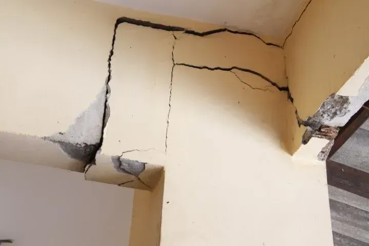 Severe structural cracks in a concrete building beam.