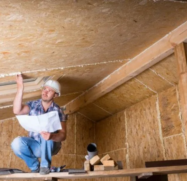 Builder inspecting OSB attic insulation and roof framing.