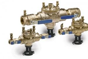 Trois valves en laiton avec des poignées bleues sont posées les unes à côté des autres sur une surface blanche.