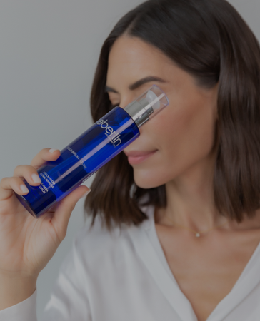 Una mujer bebe de una botella azul con la palabra aloe escrita