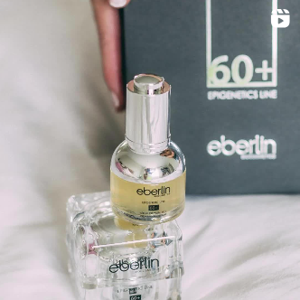 Una botella de perfume eberlin está sobre una cama