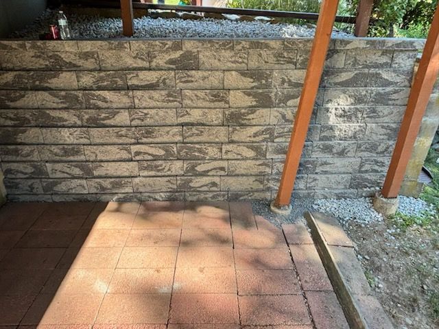 Brick wall with stone steps, wooden posts, and gravel.