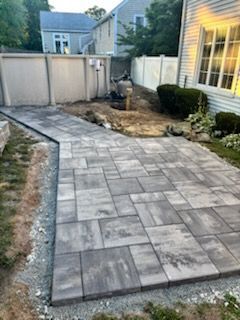 A paved patio in progress with gray interlocking pavers and a pathway.