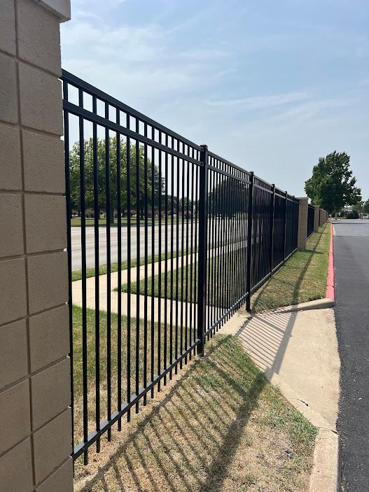 A black metal fence along a sidewalk next to a road.