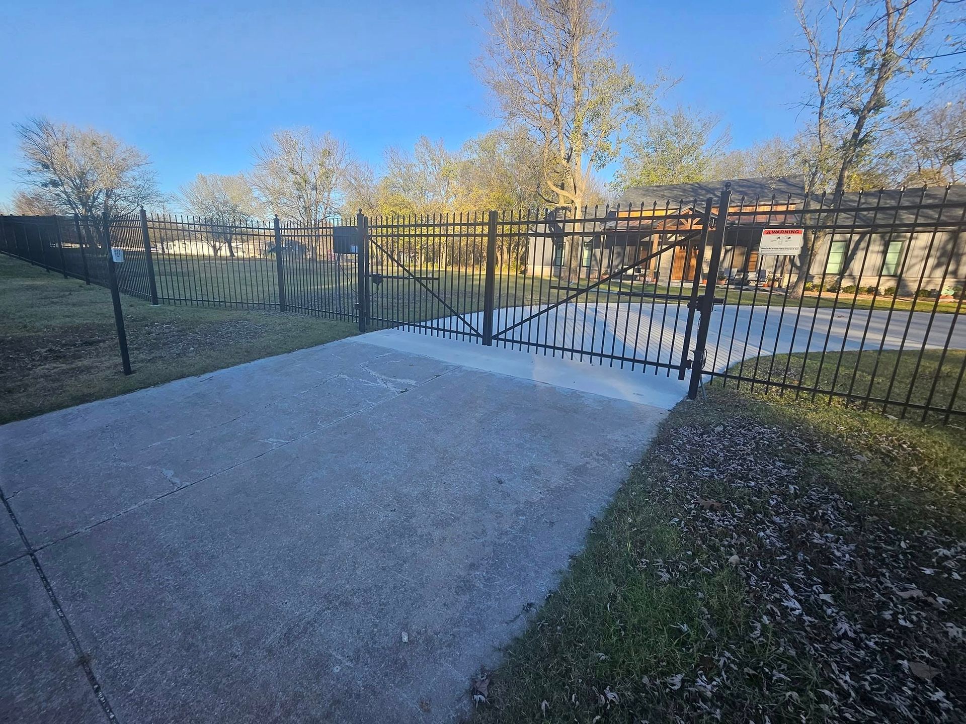 A metal fence surrounds a concrete walkway in a yard.