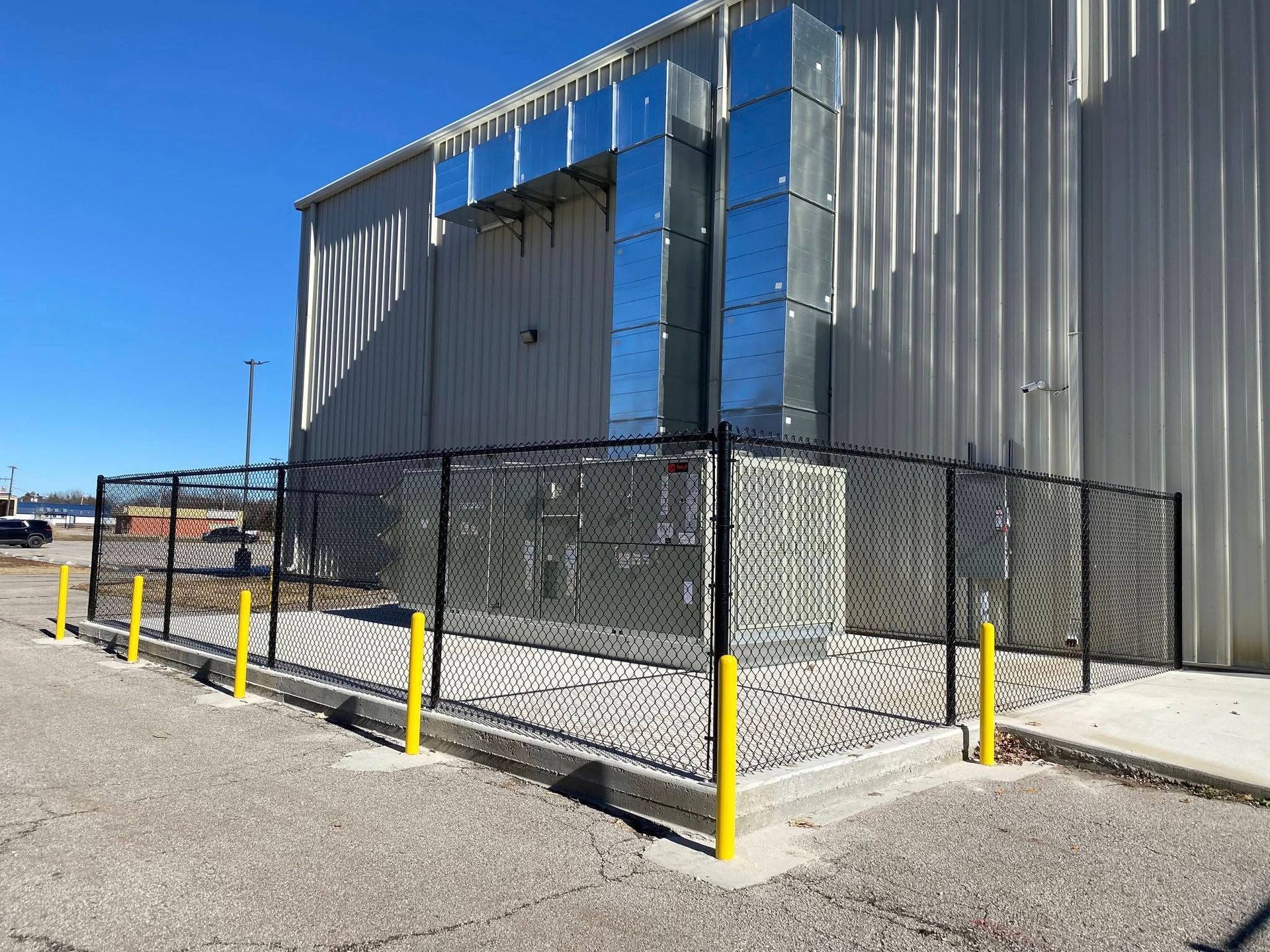 A chain link fence is surrounding a large building.
