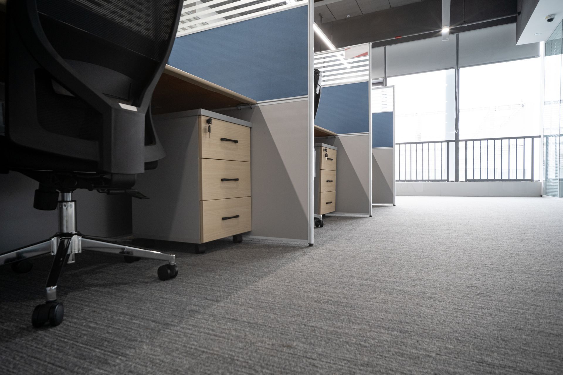 A row of office cubicles with desks and chairs in an empty office.