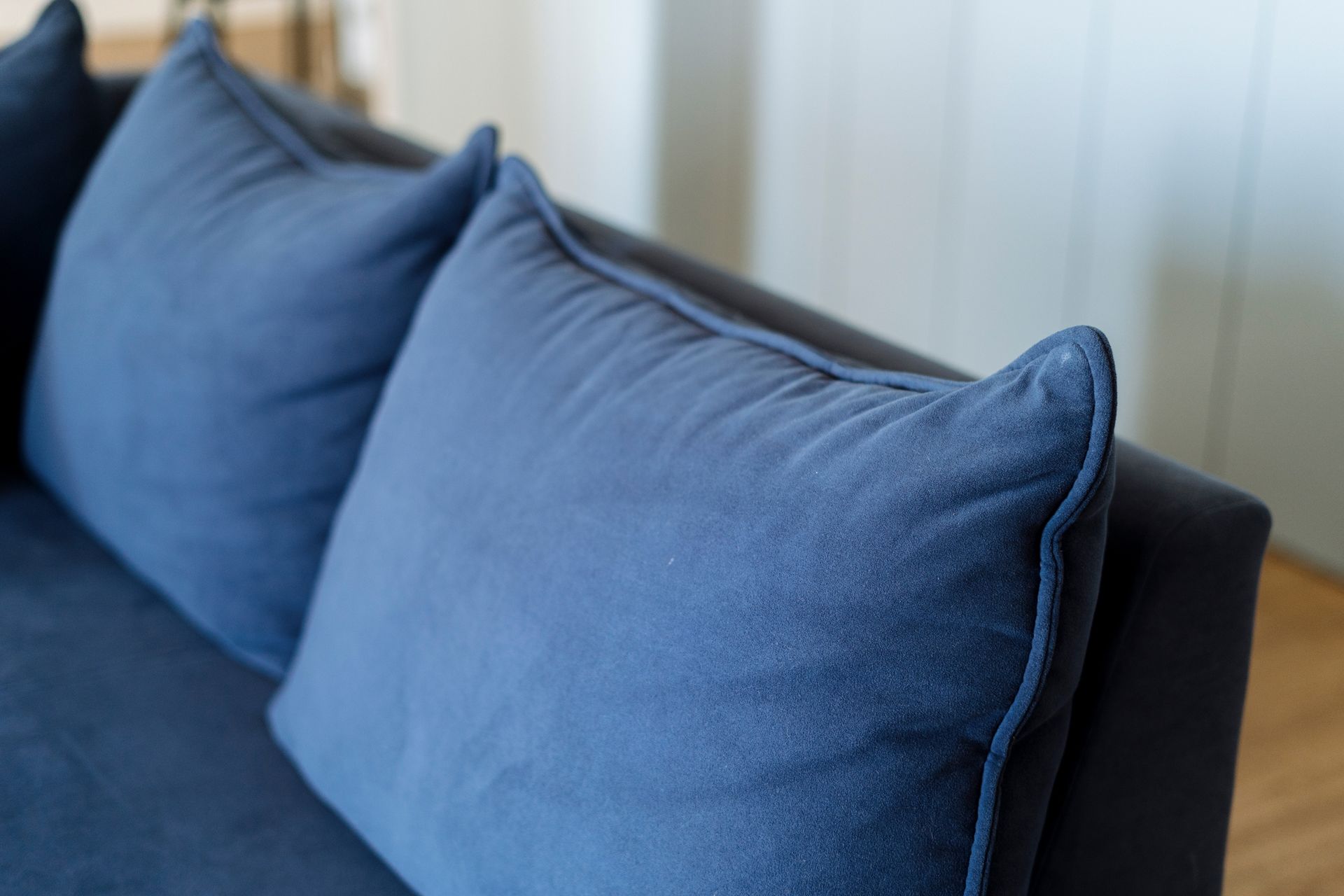 A close up of a blue couch with blue pillows in a living room.
