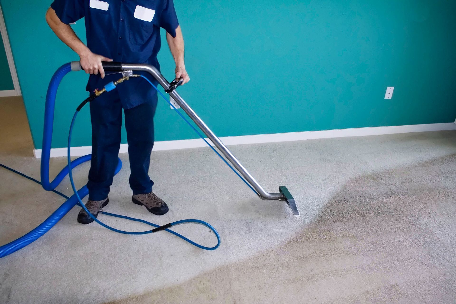 A man is cleaning a carpet with a vacuum cleaner