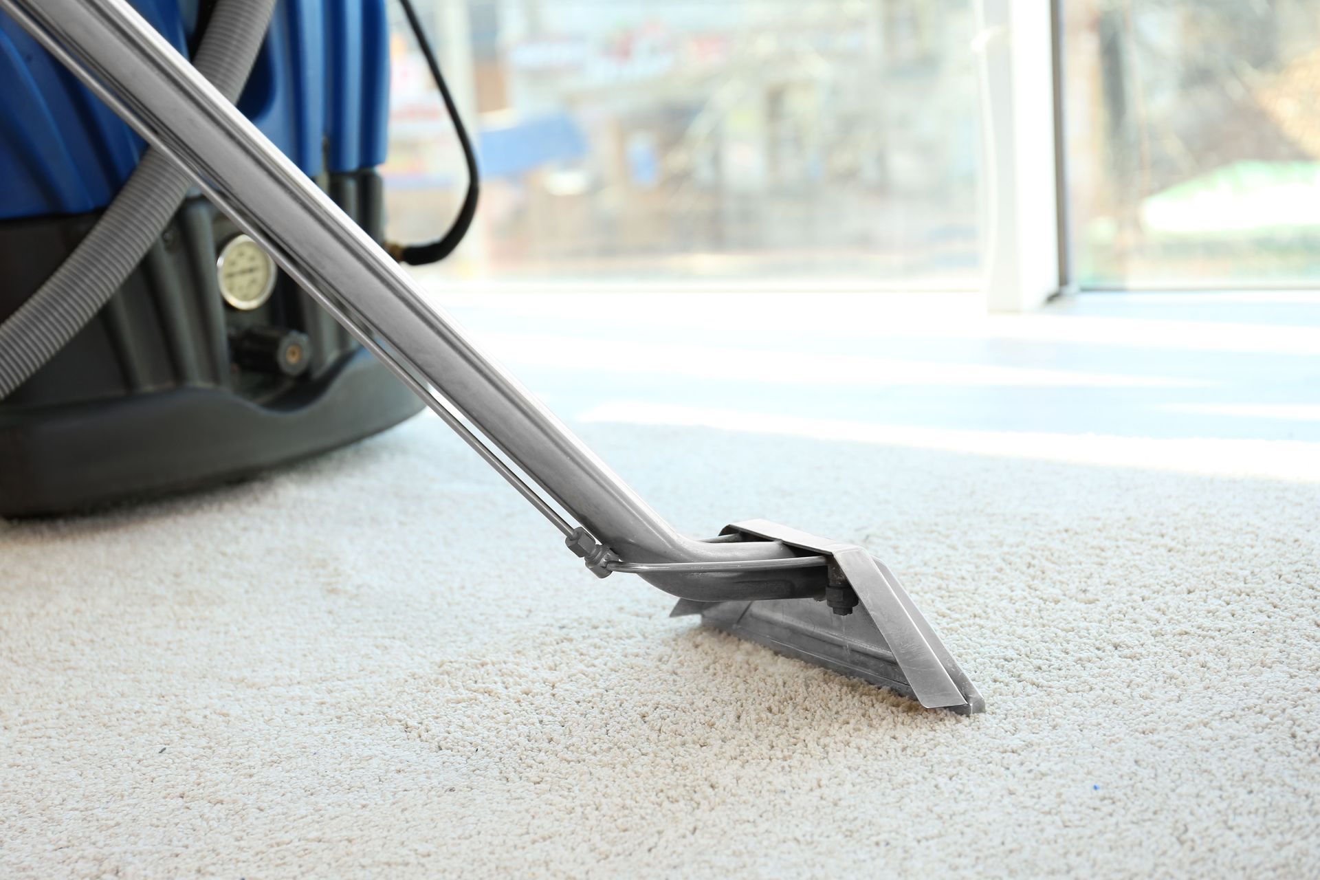 A vacuum cleaner is cleaning a carpet in a room.