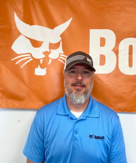 A man standing in front of a bobcat banner