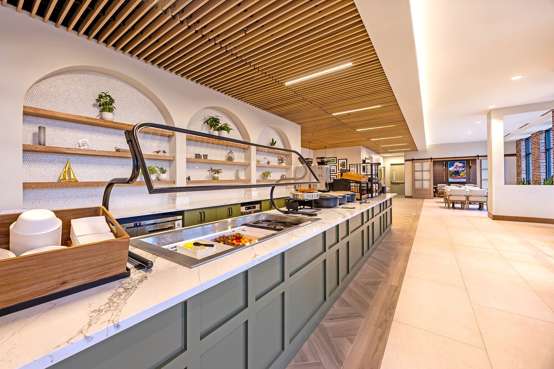 A breakfast buffet table with chafing dishes of hot food, bowls of fresh fruit, and a platter of assorted pastries.