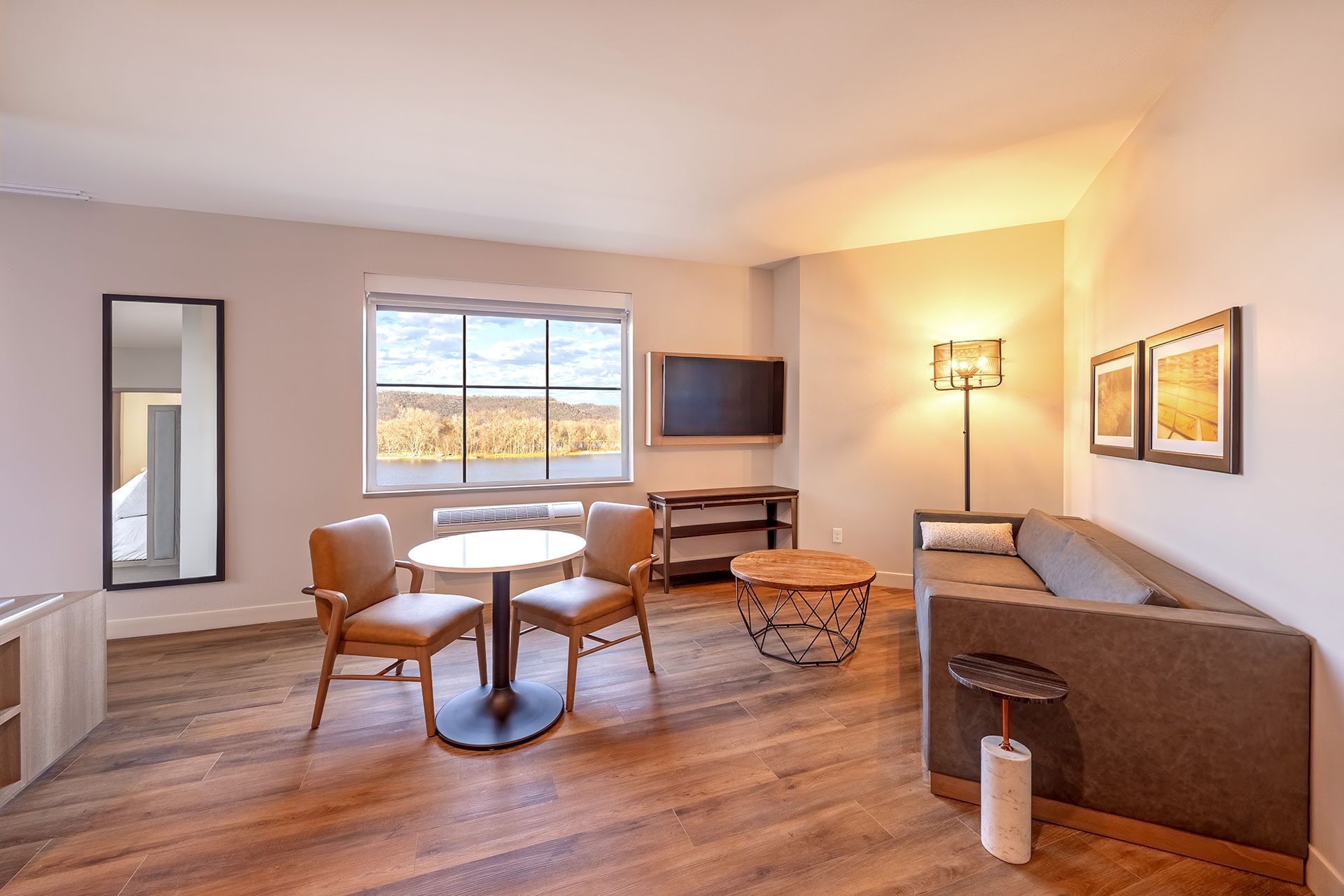 Living room with a sofa, table, chairs, window, tv, and artwork. River views