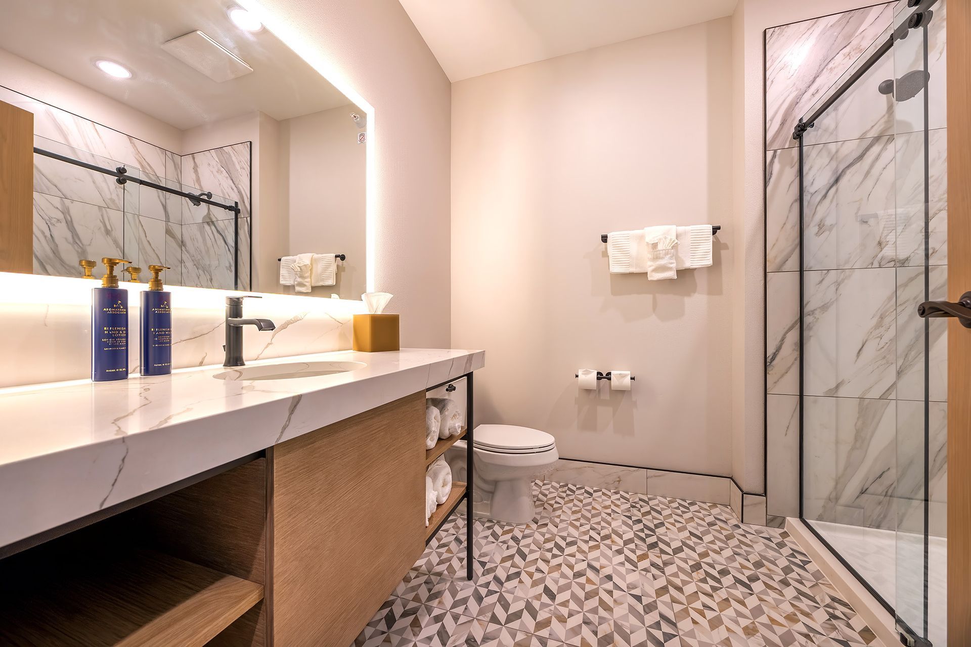 Modern bathroom with quartz countertops and patterned floor. Shower with glass door.