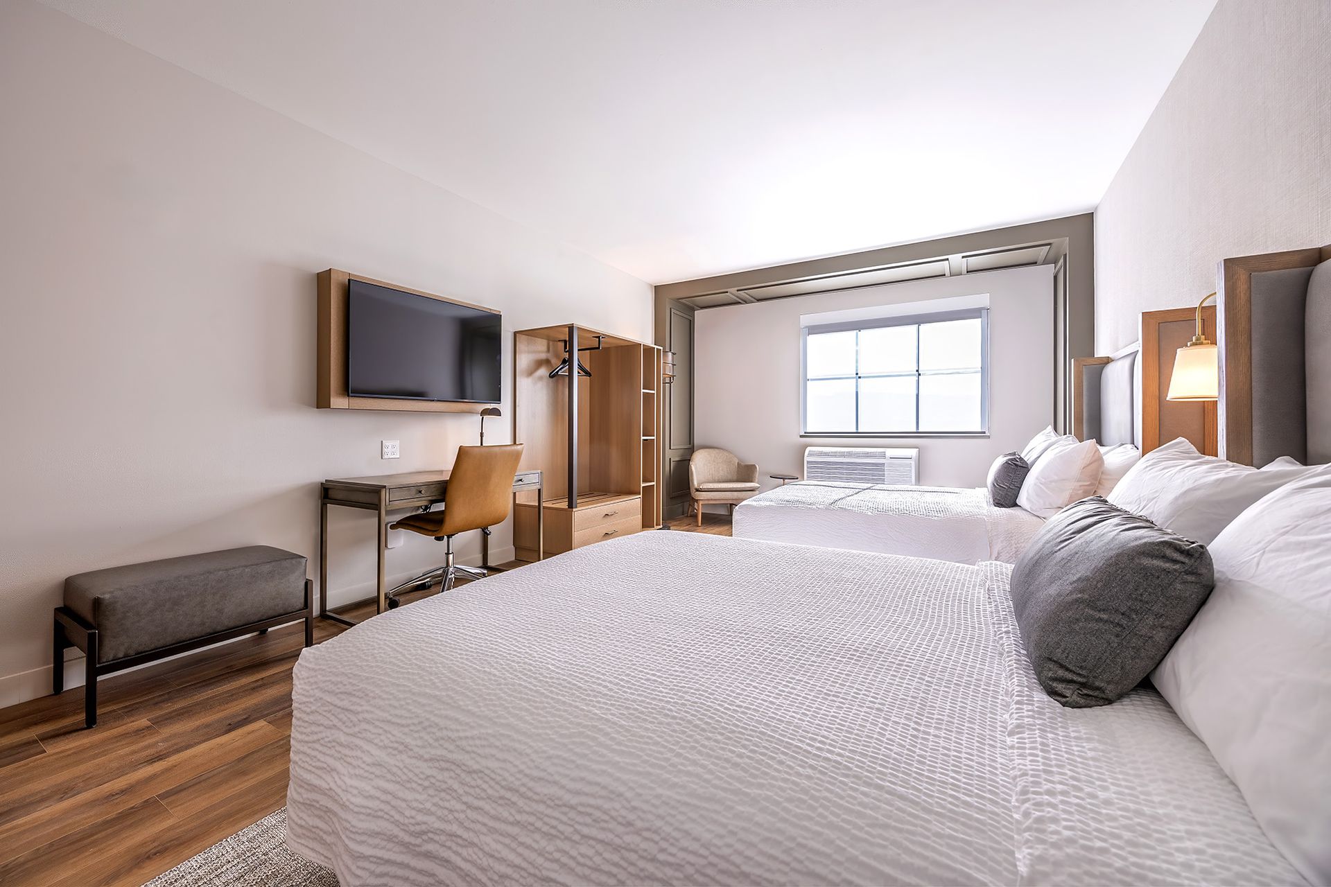 Hotel room with two beds, desk, TV, closet, and window.