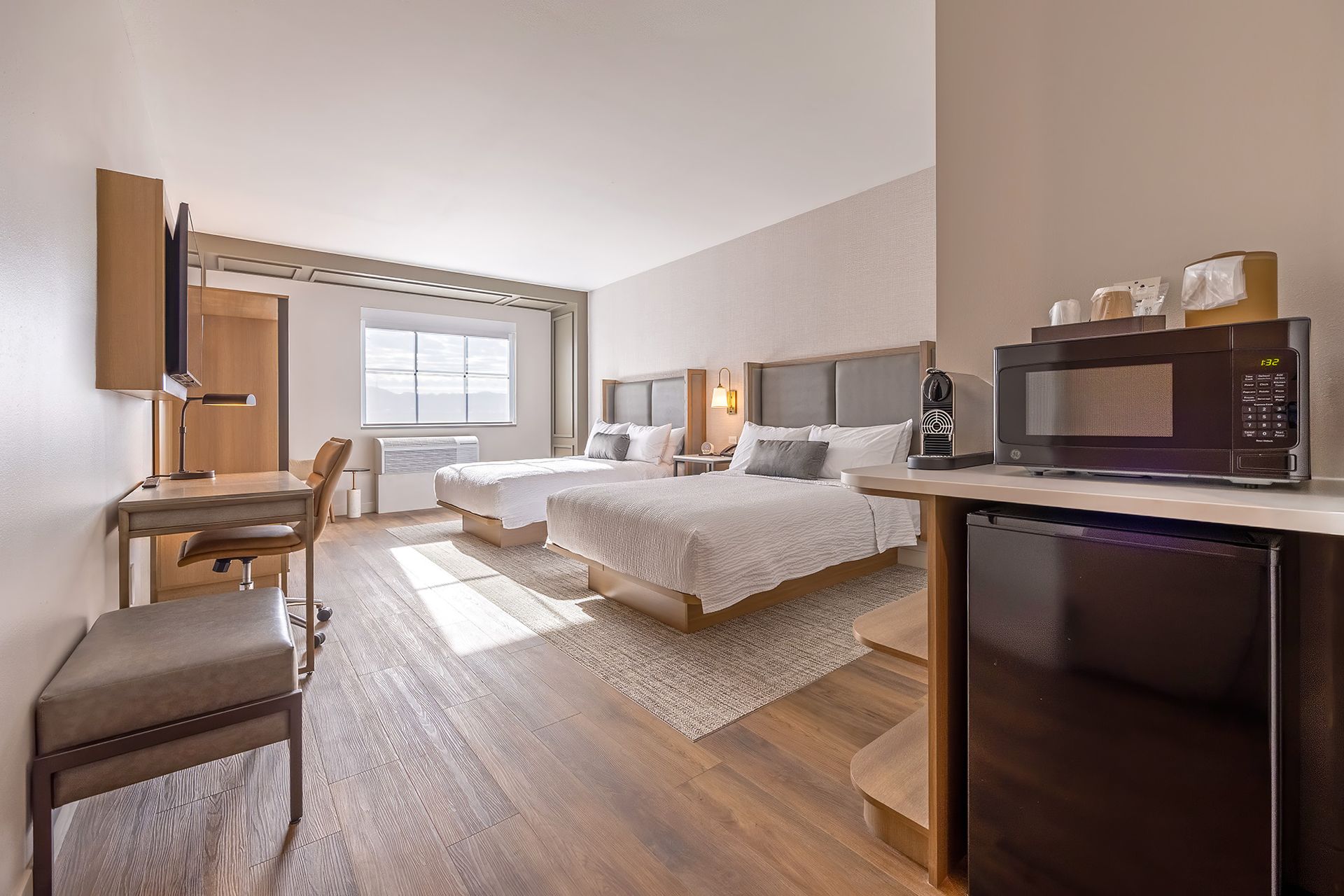 Hotel room with two beds, microwave, mini-fridge, desk, and window.