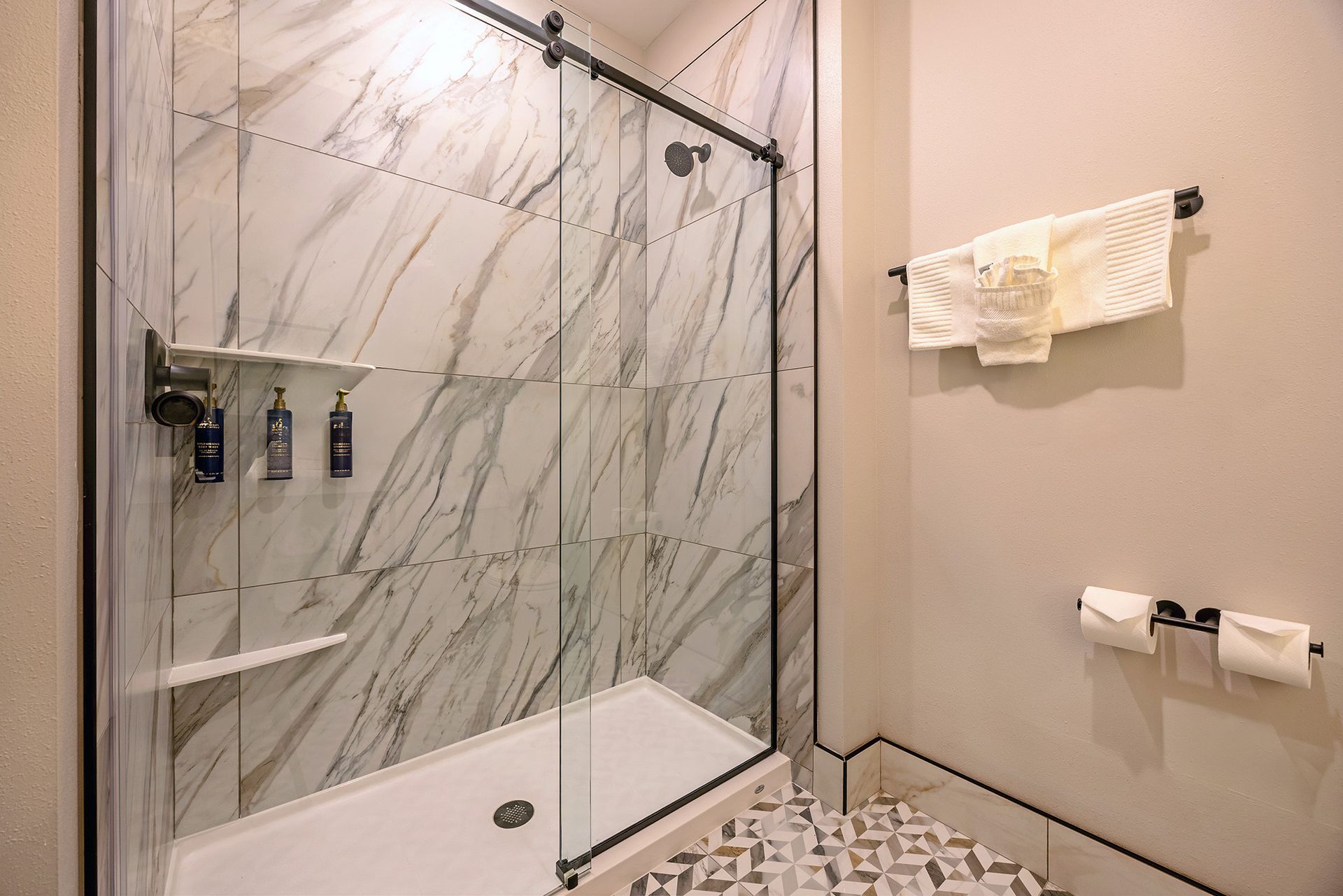 Bathroom with marble tile shower, glass door, and towel rack.