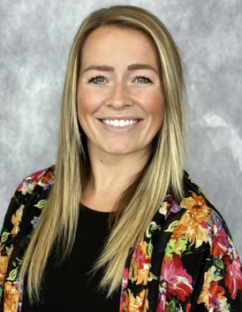 A woman wearing a floral jacket is smiling for the camera