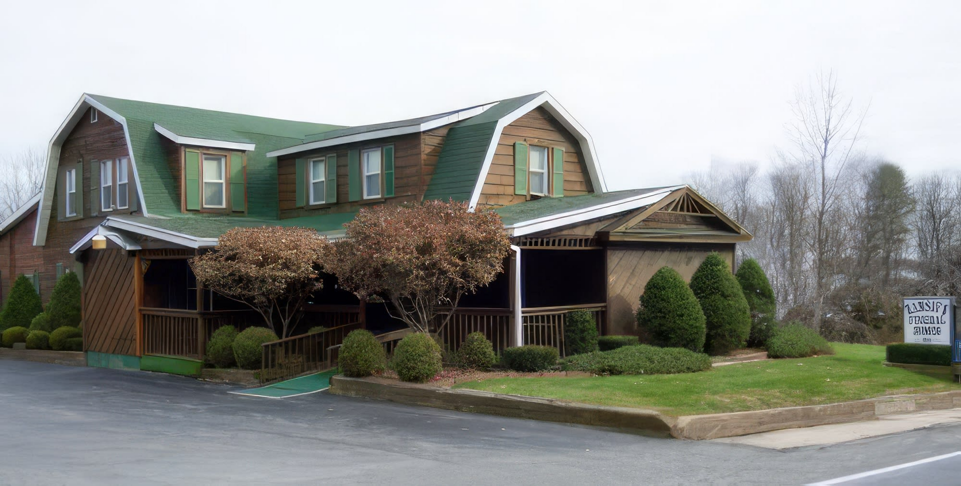A large house with a green roof is sitting next to a road.