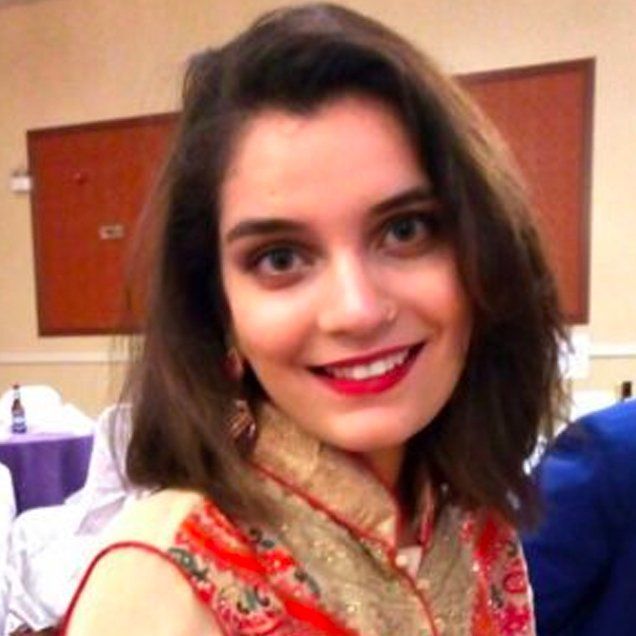 A woman in a red and gold dress is smiling for the camera