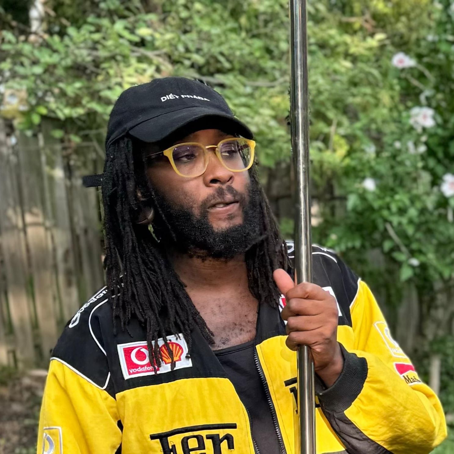 A man with dreadlocks and glasses is holding a pole.